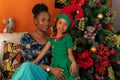 Afro-descendant Colombian Latins mother and daughter sitting on the sofa next to the Christmas tree