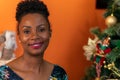 Afro-descendant Colombian woman sitting on the sofa next to the Christmas tree smiling happy