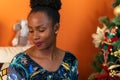 Afro-descendant Colombian woman sitting on the sofa next to the Christmas tree smiling happy