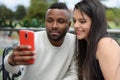 Afro-descendant man and happy latin colombian woman making photo with cell phone sitting on terrace chairs Royalty Free Stock Photo