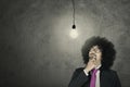 Afro entrepreneur looking at light bulb Royalty Free Stock Photo