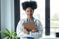 Afro female doctor holding clipboard while looking at camera standing in the consultation Royalty Free Stock Photo