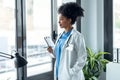 Afro female doctor holding clipboard while looking forward window standing in the consultation Royalty Free Stock Photo