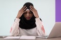 afro girl wearing a hijab is disappointed and sad sitting in her home office and using a laptop Royalty Free Stock Photo