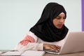 afro girl wearing a hijab is disappointed and sad sitting in her home office and using a laptop Royalty Free Stock Photo