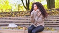 Afro hair young woman wearing knitted sweater and scarf sit on bench in autumn park and shiver from the cold on late