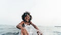 Afro kid splashing water on camera while swimming inside the ocean during summer vacation - African child having fun playing on Royalty Free Stock Photo