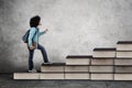 Afro male college student walks on books stair