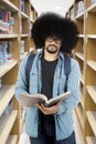 Afro male student reading a book at library