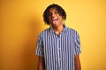 Afro man with dreadlocks wearing casual striped t-shirt over isolated yellow background sticking tongue out happy with funny Royalty Free Stock Photo