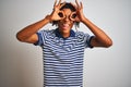 Afro man with dreadlocks wearing striped blue polo standing over isolated white background doing ok gesture like binoculars Royalty Free Stock Photo