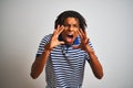 Afro man with dreadlocks wearing striped blue polo standing over isolated white background Shouting angry out loud with hands over Royalty Free Stock Photo