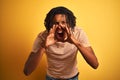 Afro man with dreadlocks wearing striped t-shirt standing over isolated yellow background Shouting angry out loud with hands over Royalty Free Stock Photo