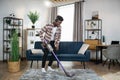 Afro man in headphones cleaning carpet with vacuum cleaner