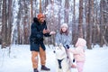 afro man with his caucasian wife having fun with a beautiful daughter playing husky in snowy park Royalty Free Stock Photo