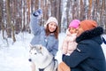 afro man with his caucasian wife having fun with a beautiful daughter playing husky in snowy park Royalty Free Stock Photo