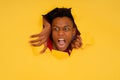 Afro man looking through a torn hole in paper wall. Royalty Free Stock Photo