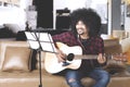 Afro man playing guitar at home