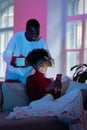 Afro man surprise girlfriend with gift. Woman sit on couch, closed eyes receive unexpected present Royalty Free Stock Photo