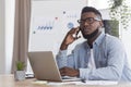 Afro manager talking on phone at workplace with concerned face expression