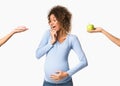 Afro pregnant woman choosing between sweet and fruit Royalty Free Stock Photo
