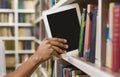 Afro student placing digital tablet on bookshelf Royalty Free Stock Photo