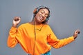 Afro woman in headphones listening to music and dancing over grey studio background Royalty Free Stock Photo