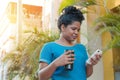 Afro woman with a thermos of coffee and checking her cellular phone Royalty Free Stock Photo