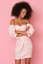 Afroamercian young woman in pink dress on pink background.