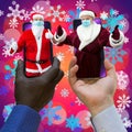 Afroamerican and caucasian-white hands holding phones with 2 Santa Clauses. Royalty Free Stock Photo