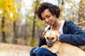 Afroamerican girl in autumn park playing with her dog Royalty Free Stock Photo