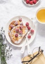 Afternoon tea break rest table - french toast with fresh raspberry, green tea and book on light background, top view Royalty Free Stock Photo