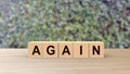 Again word Wooden cubes on table over background leaves green HD, mock up, template, banner with copy space for text, repeat, do