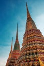 Against the backdrop of a clear blue sky, the distinct spires of three ornate Buddhist stupas grace the Temple of the Emerald