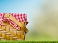 Against the backdrop of a light blue sky, a straw picnic basket on green grass. Summer holidays, walks, romance, family holidays, Royalty Free Stock Photo