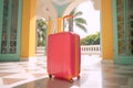 Against the backdrop of palm trees and a luxury resort, red suitcase holiday concept