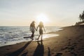 Against the backdrop of the sunset over the ocean goes on the water edge a couple of men and women holding hands Royalty Free Stock Photo