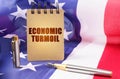 Against the background of the American flag is a notepad with the inscription - economic turmoil
