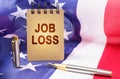 Against the background of the American flag is a notepad with the inscription - job loss Royalty Free Stock Photo