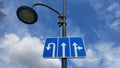 Against the background of a blue sky with white clouds, a lamppost with car turn signs