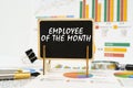 Against the background of business graphs, a board with the inscription - Employee of the Month Royalty Free Stock Photo