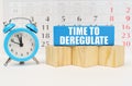 Against the background of the calendar, an alarm clock and a blue block with the inscription -Time to Deregulate Royalty Free Stock Photo