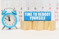 Against the background of the calendar, an alarm clock and a blue block with the inscription -Time To Reboot Yourself