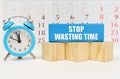 Against the background of the calendar is an alarm clock, cubes and a blue block with the inscription -Stop Wasting Time Royalty Free Stock Photo