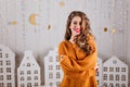 Against background of cardboard Christmas decorations in form of garlands and white houses, beautiful brown-haired woman