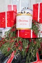 Against the background of a Christmas tree and decorations, there are many large, bright and beautiful red gift boxes. Christmas
