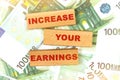 Against the background of euro bills, the text is written on wooden blocks - INCREASE YOUR EARNINGS