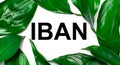 Against the background of green natural leaves, a white card with the text IBAN International Bank Account Number