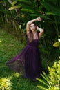 Against the background of green thickets stands in a long dress a girl with long hair and touches them with her hands Royalty Free Stock Photo