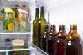 Against the background of an open white refrigerator, bottles of wine, beer and glass jugs with soft drinks of their citrus fruits Royalty Free Stock Photo